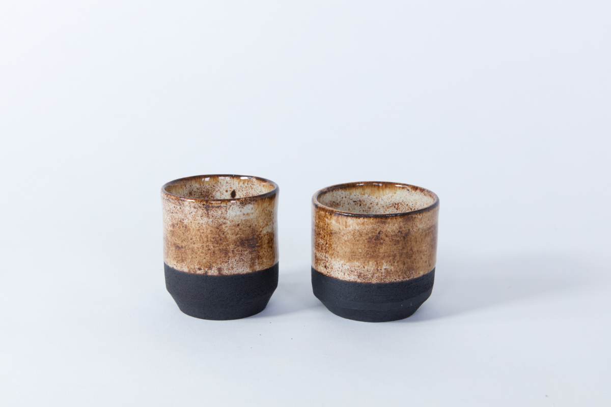 Foto zeigt zwei gedrehte Tassen aus schwarzem Ton mit braungesprenkelter Glasur