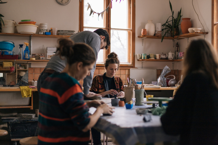 Foto zeigt Maike Panz beim Töpferkurs mit einer Gruppe am Tisch sitzend