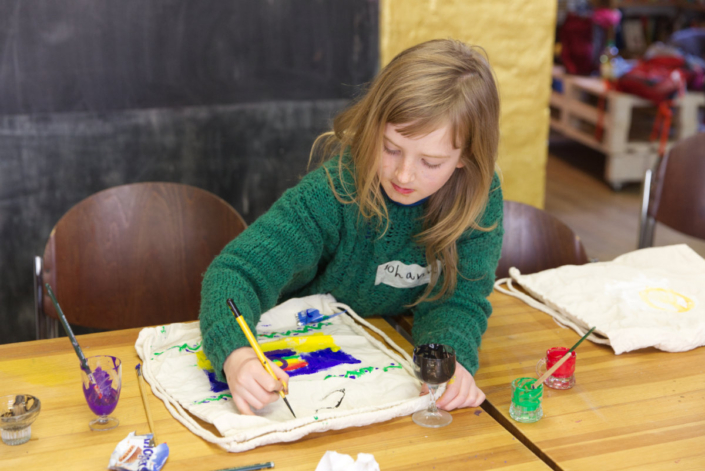 Foto zeigt ein Kind, das einen Beutel mit Textilfarbe bemalt