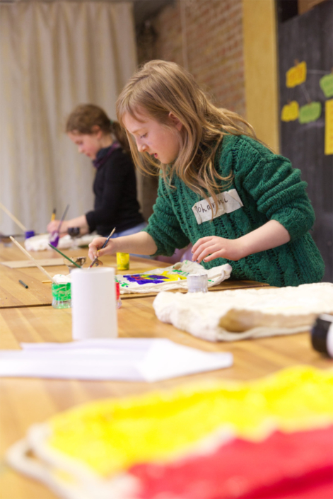 Foto zeigt ein Kind beim Workshop, das einen Beutel mit Textilfarbe bemalt