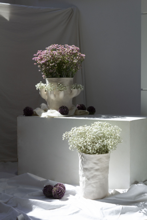 Foto zeigt zwei Porzellan-Vase mit Blumen. Eine der beiden hat Arme, in denen Blumen stecken