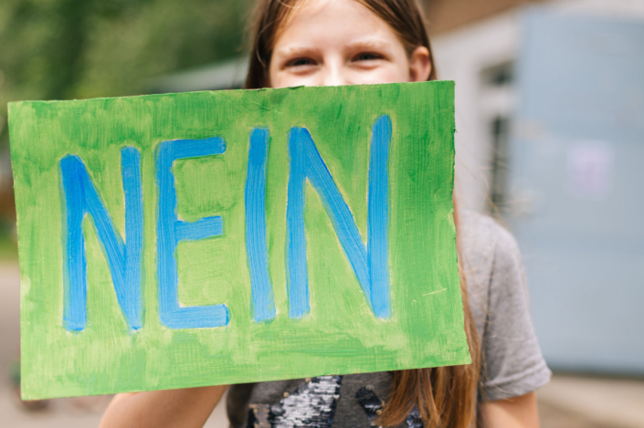 Foto zeigt, wie ein Kind ein selbstgemaltes Schild hochhält, auf dem "Nein" steht