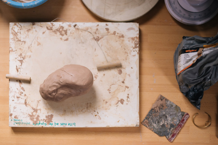 Foto zeigt eine Gipsplatte, auf der ein Tonklumpen und ein Schneidedraht liegen