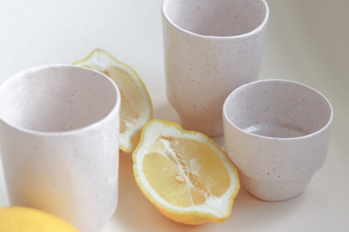 Drei dünnwandige Becher, zwischen denen eine aufgeschnittene Zitrone liegt