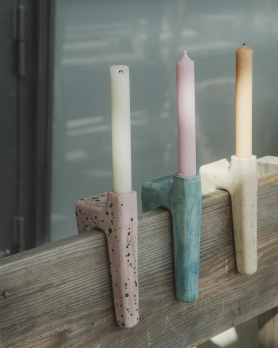 drei außergewöhnliche Kerzenhalter, deren Form es ermöglicht, sie über eine Rückenlehne zu hängen