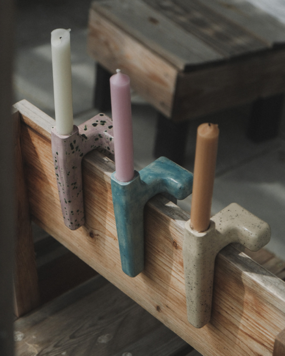 drei bunte Kerzenständer, über einem aufrechten Brett hängend