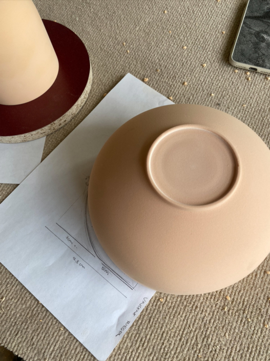 gedrechselte Form aus Ureol liegt auf einem Bild mit Skizzen