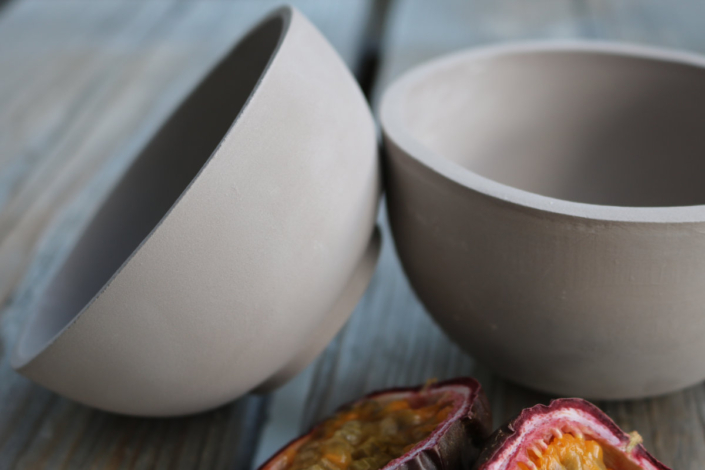 zwei Schalen mit scharfkantigem Trinkrand sind aneinandergelegt, vor Ihnen liegt eine Maracuja