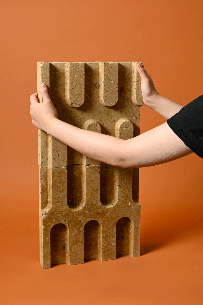 Foto zeigt zwei Arme, wie sie zwei Lehmfliesen aufeinanderstapeln