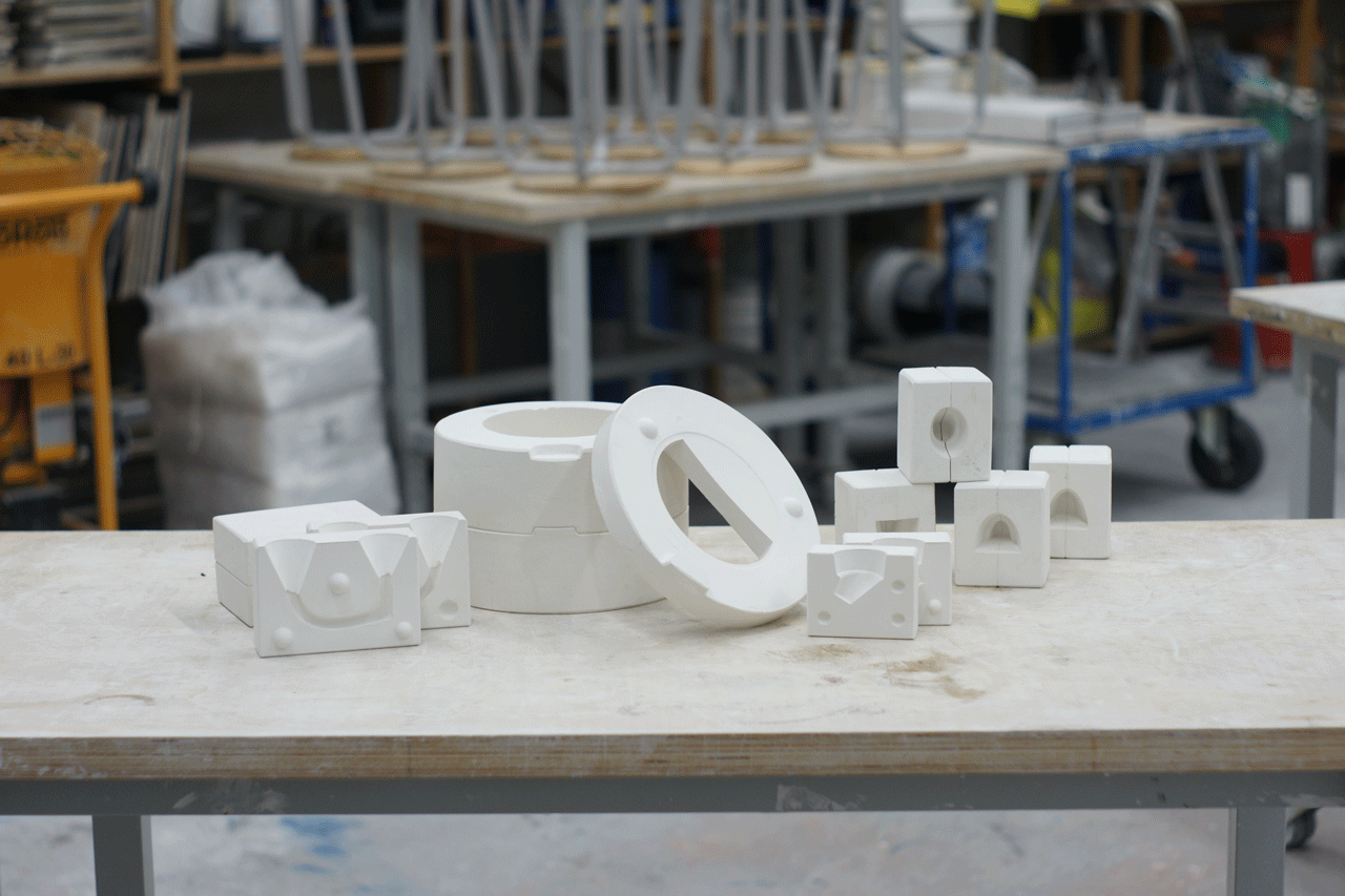 Gipsformen für Tüllen, Henkel und Teekanne mit Werkstatt unscharf im Hintergrund
