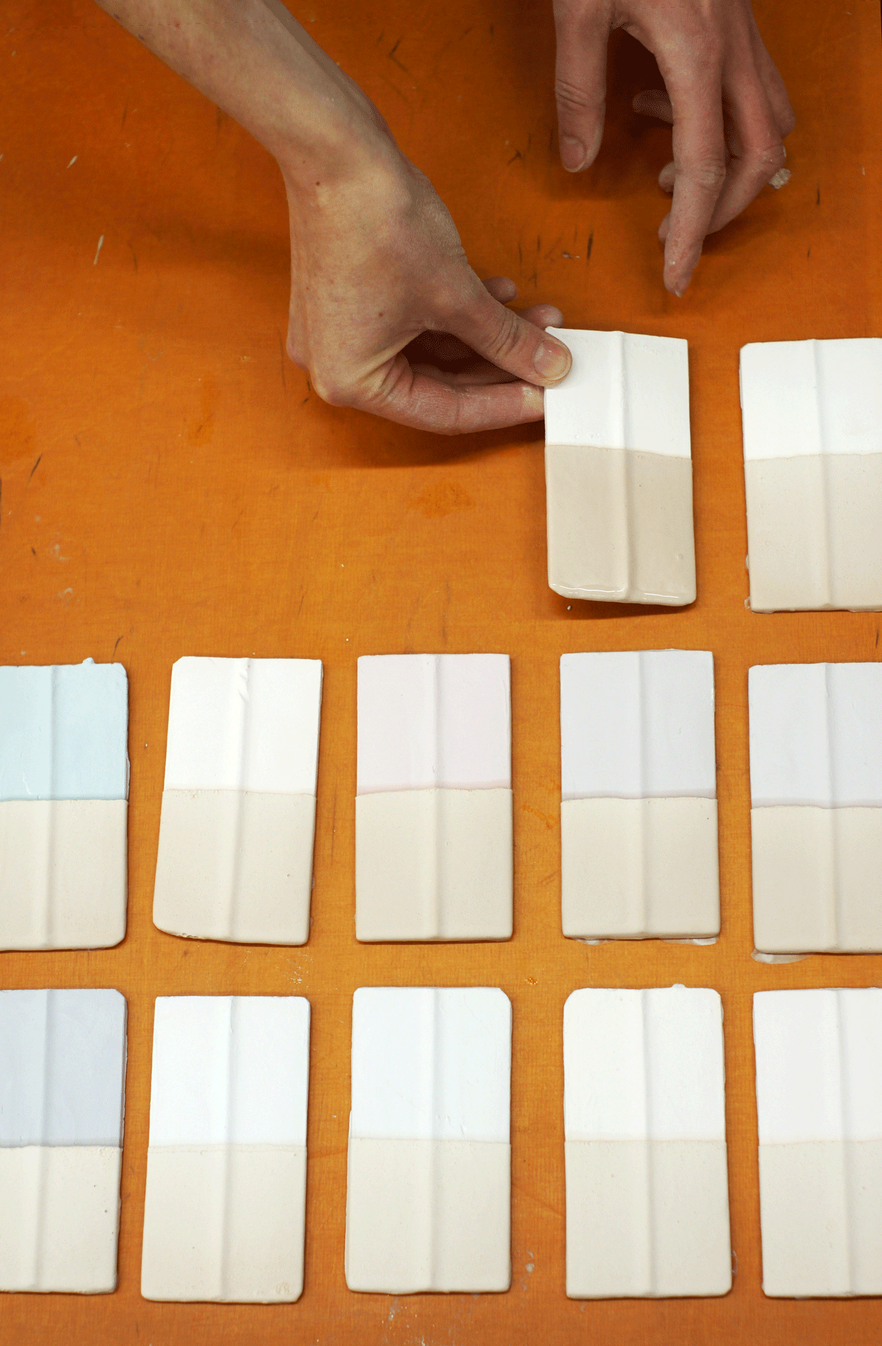 Hände legen glasierte Porzellan-Fliesen auf ein Tablet